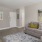 Spacious and well lit living room with wood floors and a large window with access to the kitchen