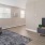 Spacious and well lit living room with wood floors and a large window with access to the kitchen
